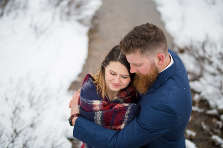 couple hugging in the snow wearing fancy clothing