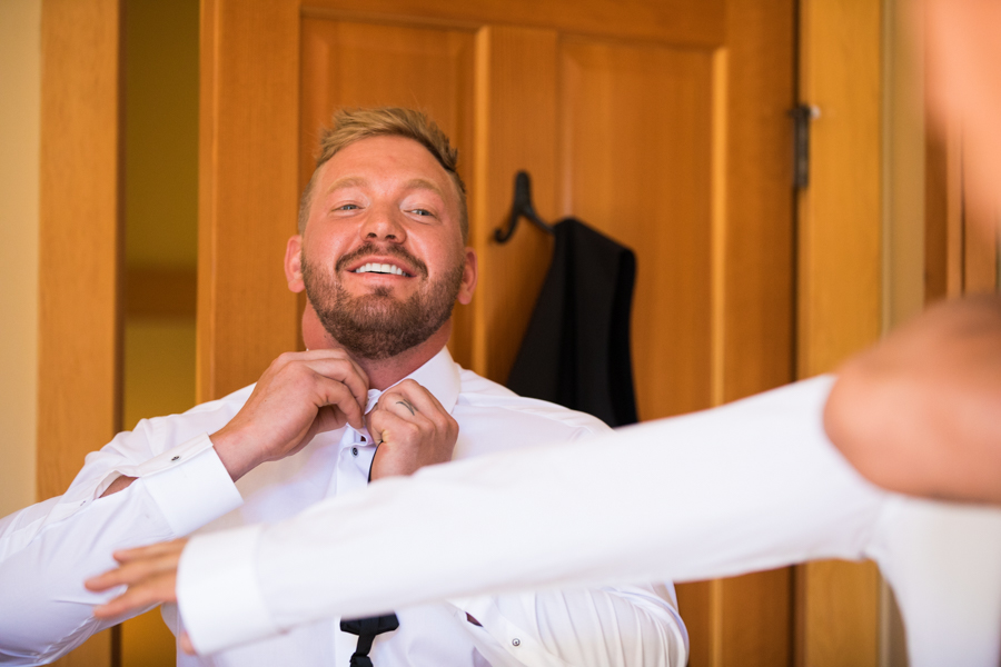 groom getting ready, in panorama bc, groom doing up his shirt