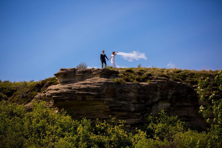a bride and groom taking a walk at the cochrane ranch house field