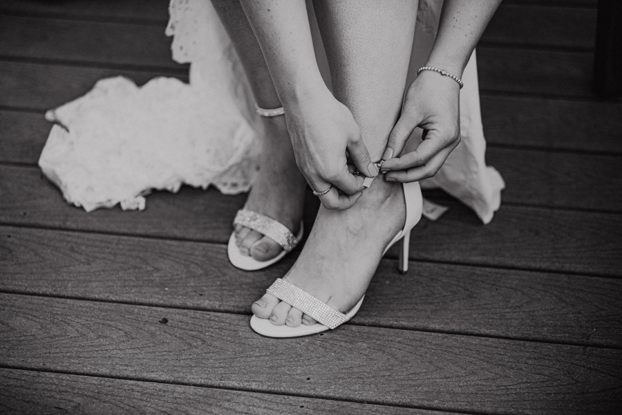 Bride doing up her shoes for a back yard wedding