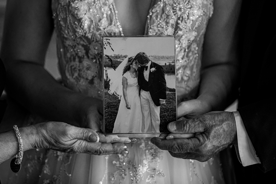 bride and parents holding a wedding photo from the parents wedding